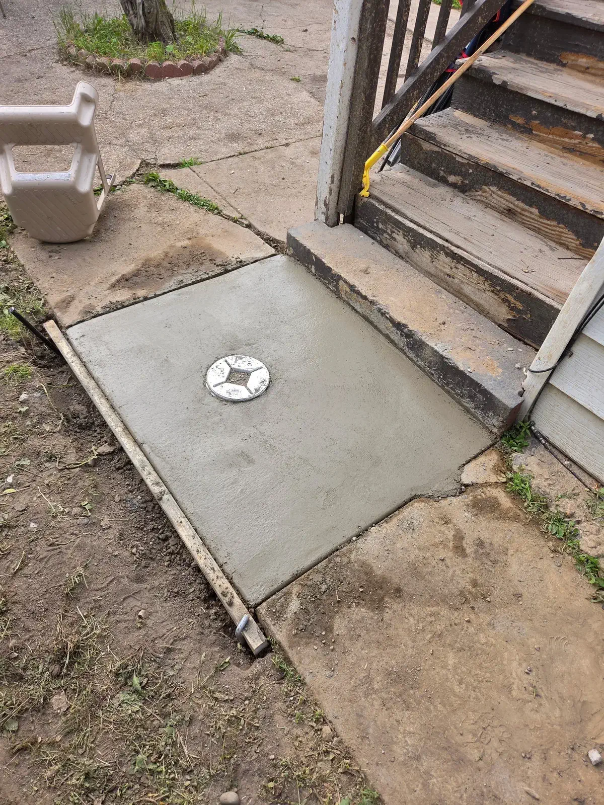 Fresh concrete patched over a new outdoor sewer cleanout